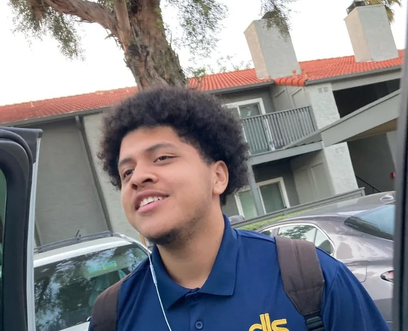 A smiling young student with a backpack heading to school