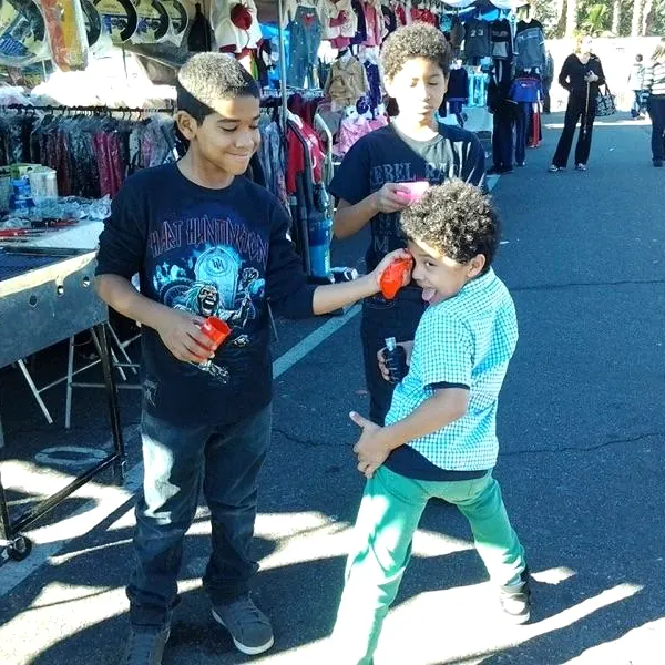 Three boys choosing school clothes and supplies at an outdoor market